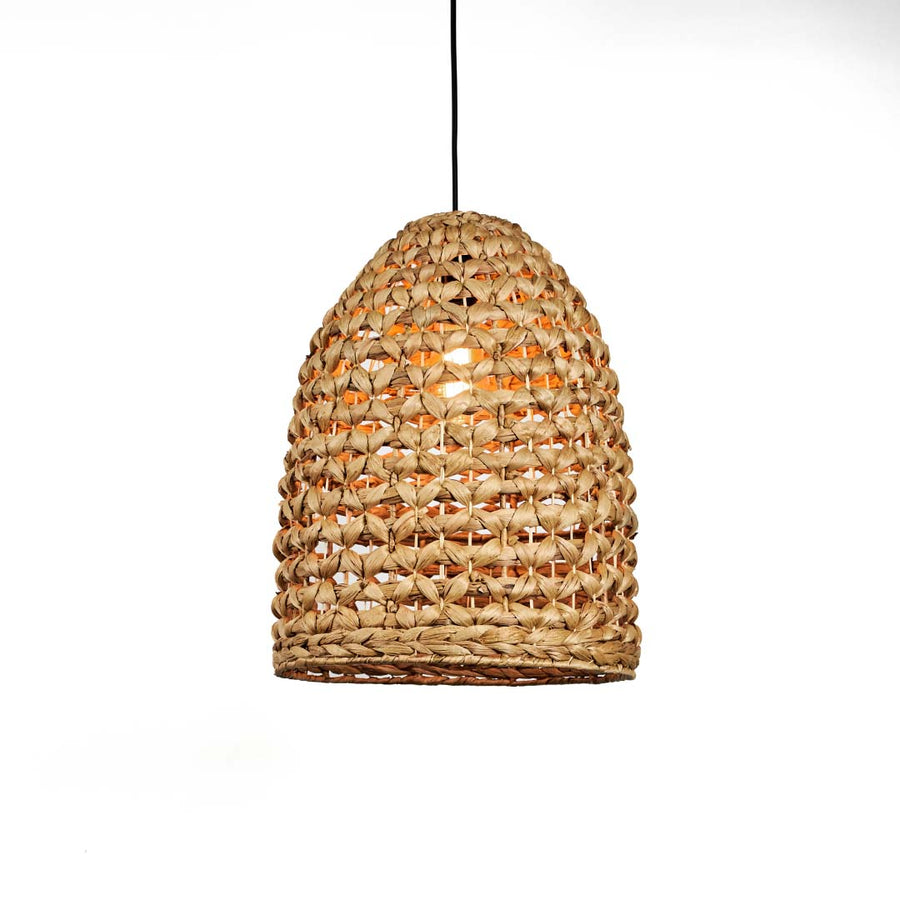 Natural rattan pendant light with rounded dome shape and tight woven texture hanging against soft neutral wall background for warm boho interior decor.