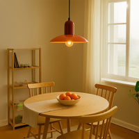Orange metal pendant light above dining table creating warm ambient lighting in modern dining room decor.