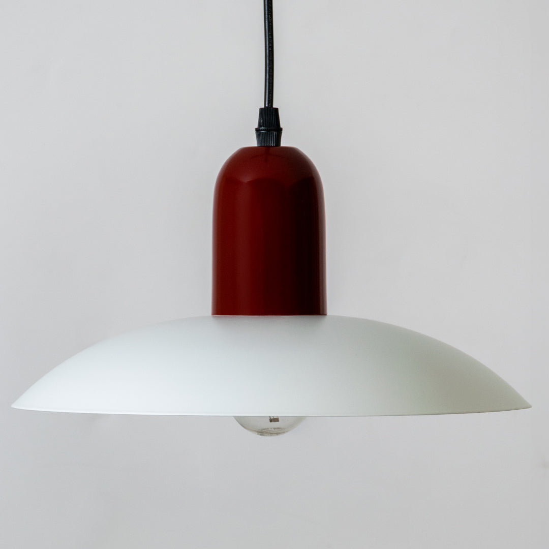 Closeup pendant light in red metal finish with wide dome shade for kitchen or dining decor lighting white background.
