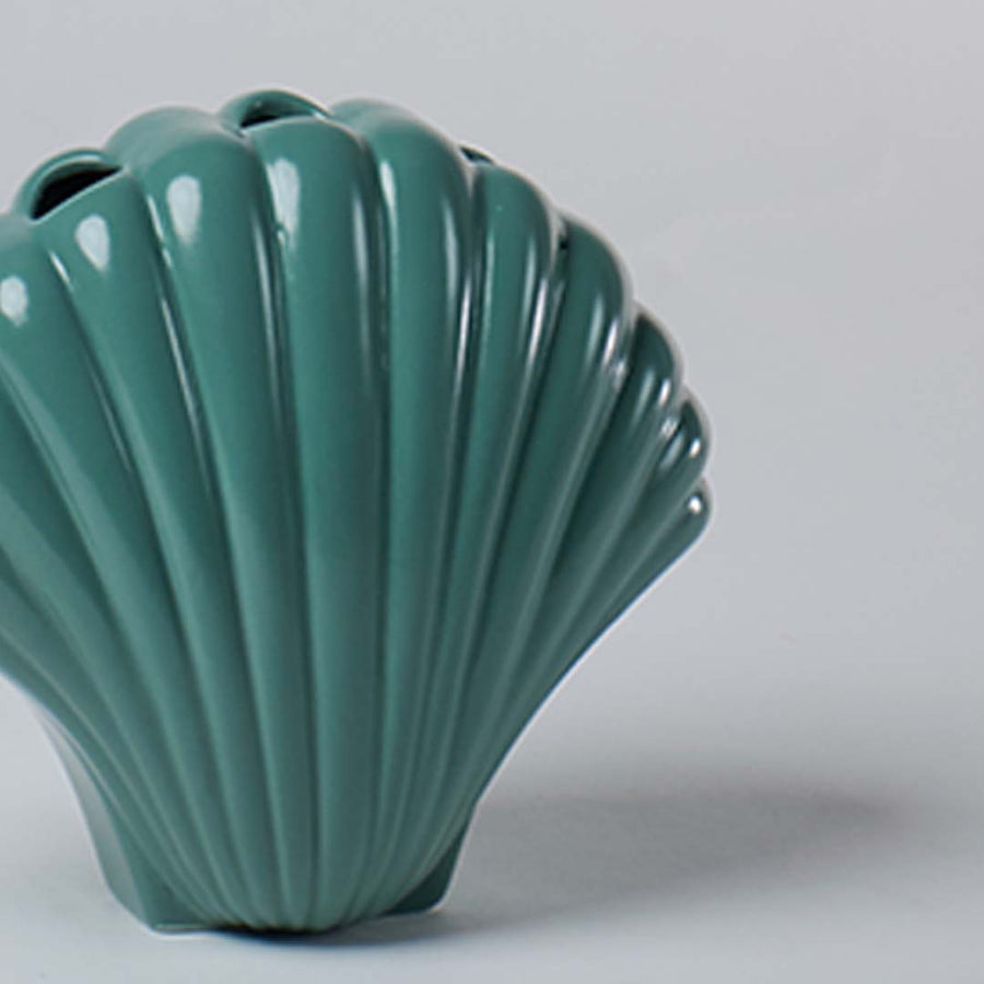 Closeup of teal ceramic shell shaped vase highlighting its ridged texture and glossy surface for elegant modern home styling.