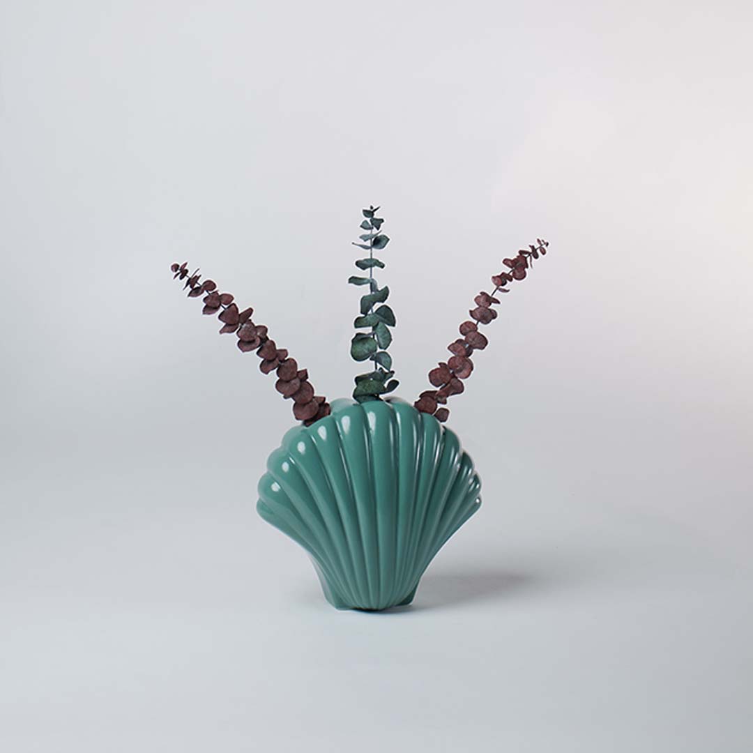 Modern teal ceramic shell vase placed on a minimal surface creating a stylish coastal accent for living room or tabletop decor.