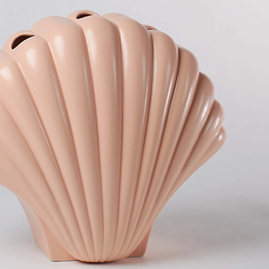 Close view of a pastel peach shell shaped vase showing the detailed ridged pattern and smooth high gloss ceramic finish.