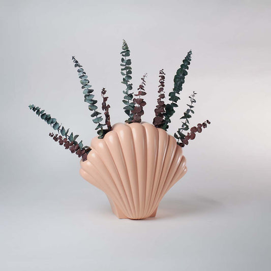 Elegant peach shell inspired vase placed in a bright minimal space adding a refined artistic touch to simple home decor.