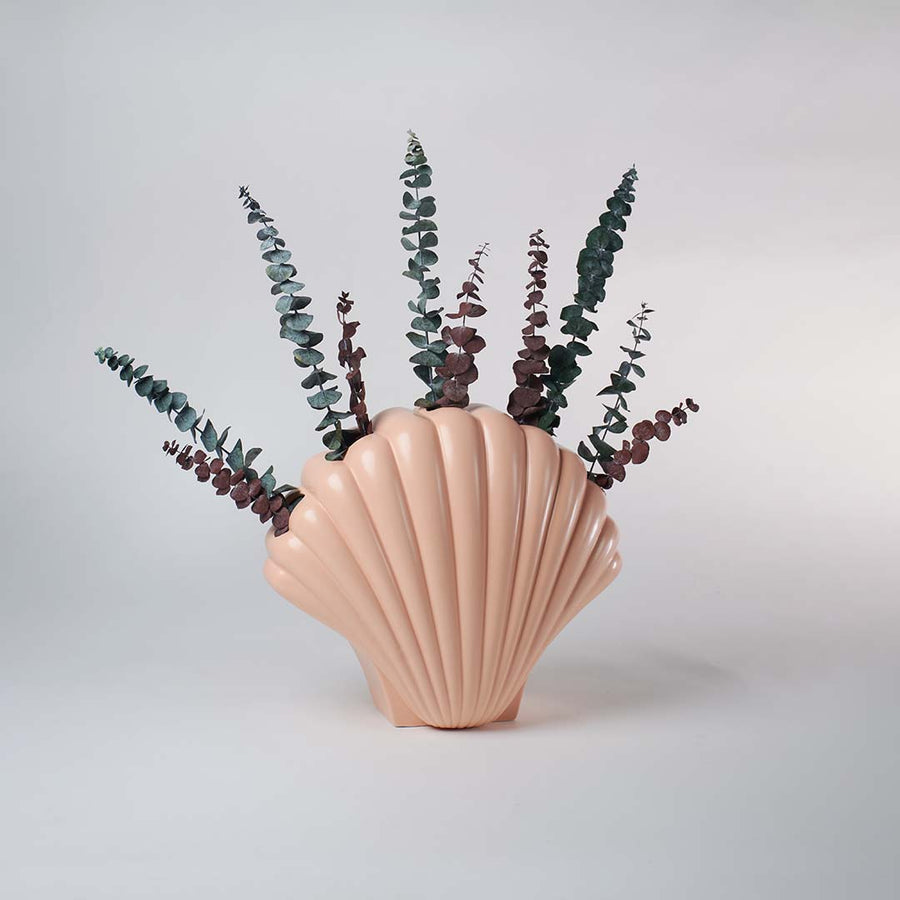Elegant peach shell inspired vase placed in a bright minimal space adding a refined artistic touch to simple home decor.