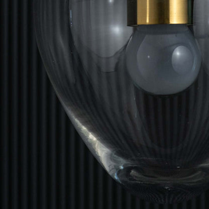 Closeup view of the heart-shaped clear glass pendant light revealing the gold fixture and visible bulb inside.