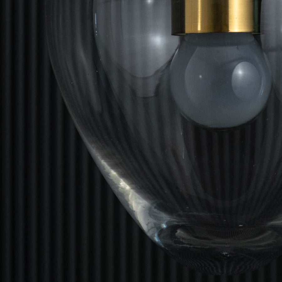 Closeup view of the heart-shaped clear glass pendant light revealing the gold fixture and visible bulb inside.