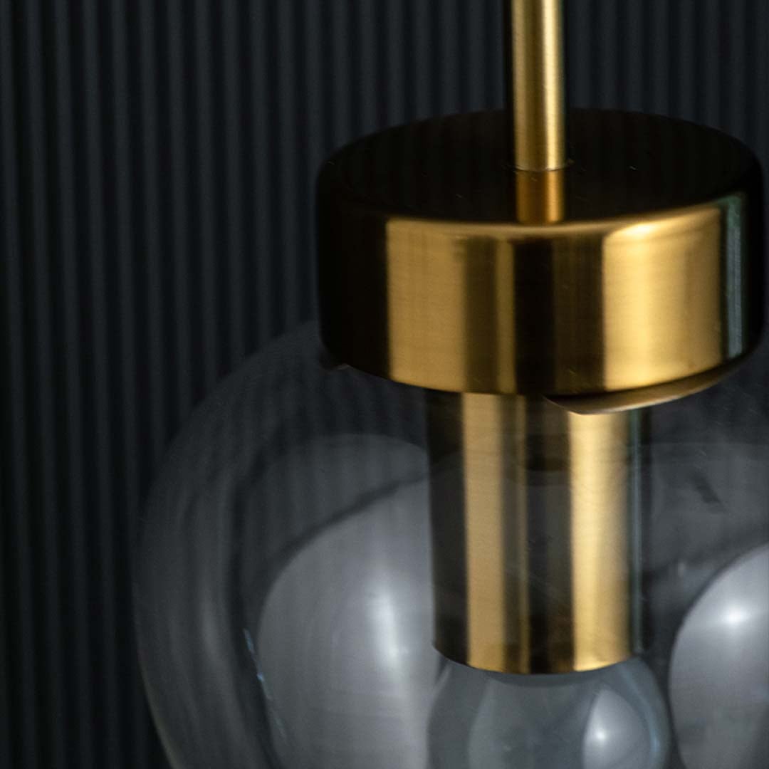 Closeup view of the heart-shaped clear glass pendant light revealing the gold fixture and visible bulb inside.