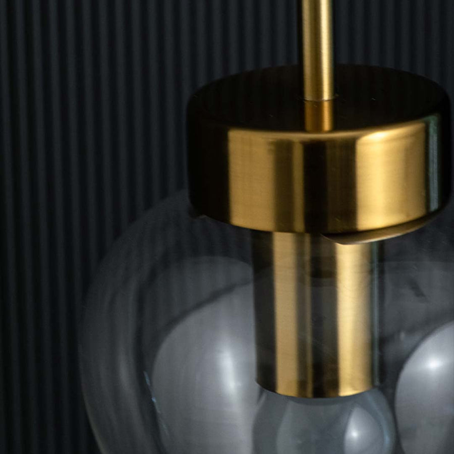 Closeup view of the heart-shaped clear glass pendant light revealing the gold fixture and visible bulb inside.