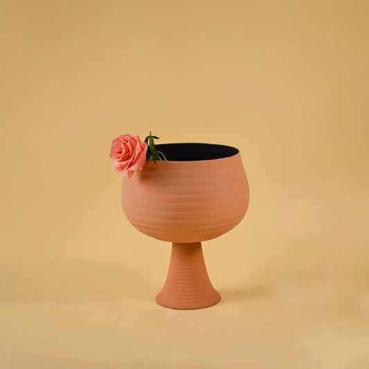 Textured terracotta metal pedestal bowl placed in a soft ambient setting bringing a warm modern touch to home interiors.