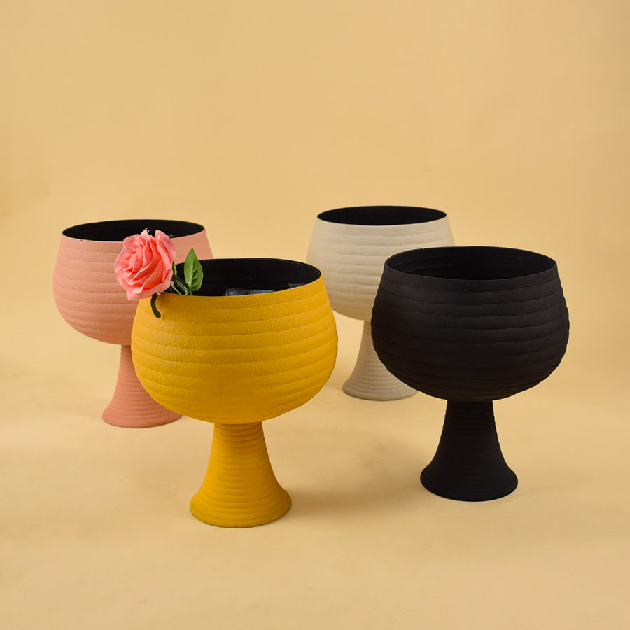 Collection of four colorful ribbed metal pedestal vases for vibrant modern home decor and artistic table centerpiece arrangement.
