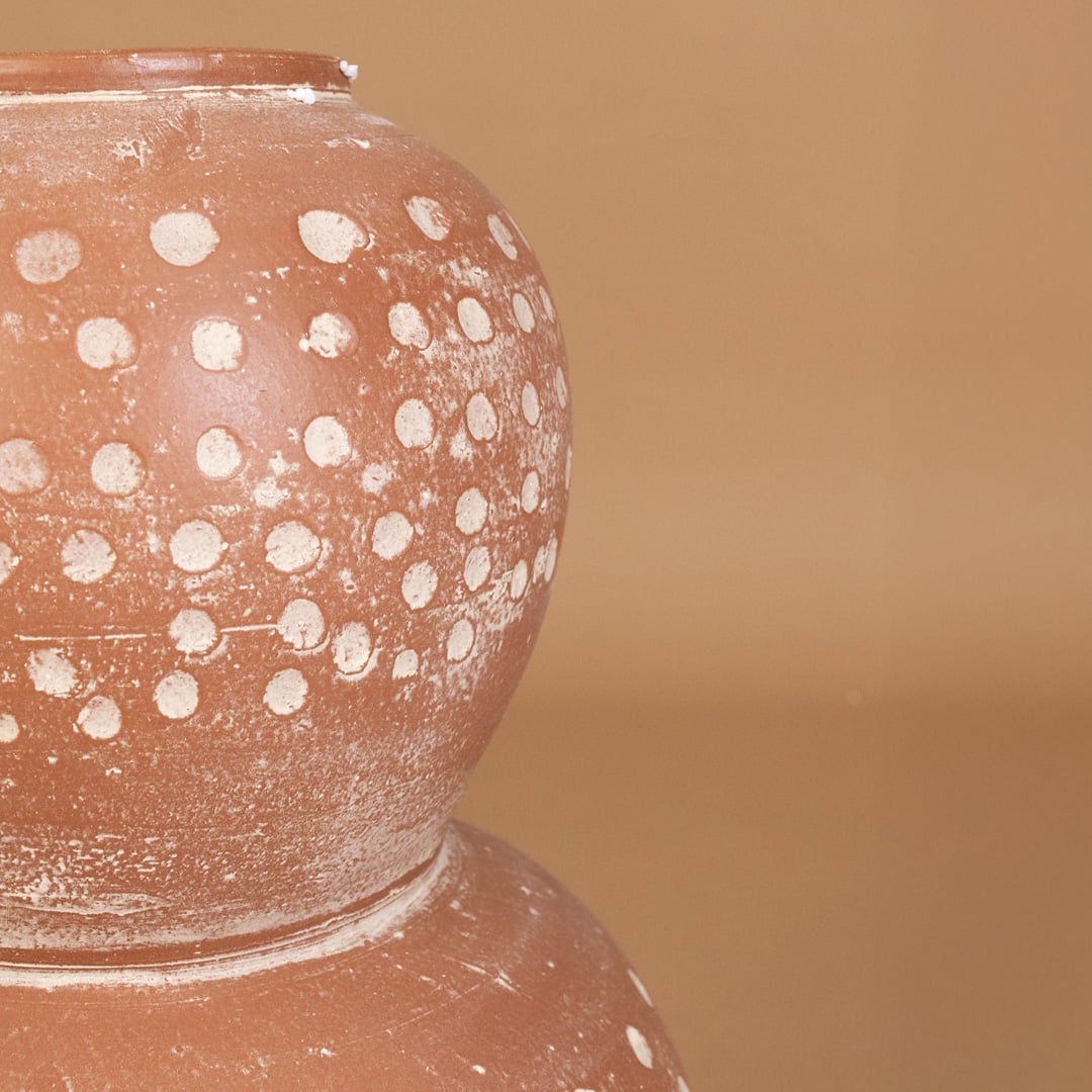 Closeup of brown terracotta decorative vase with white polka dots showing textured handcrafted detail for artistic modern home decor.