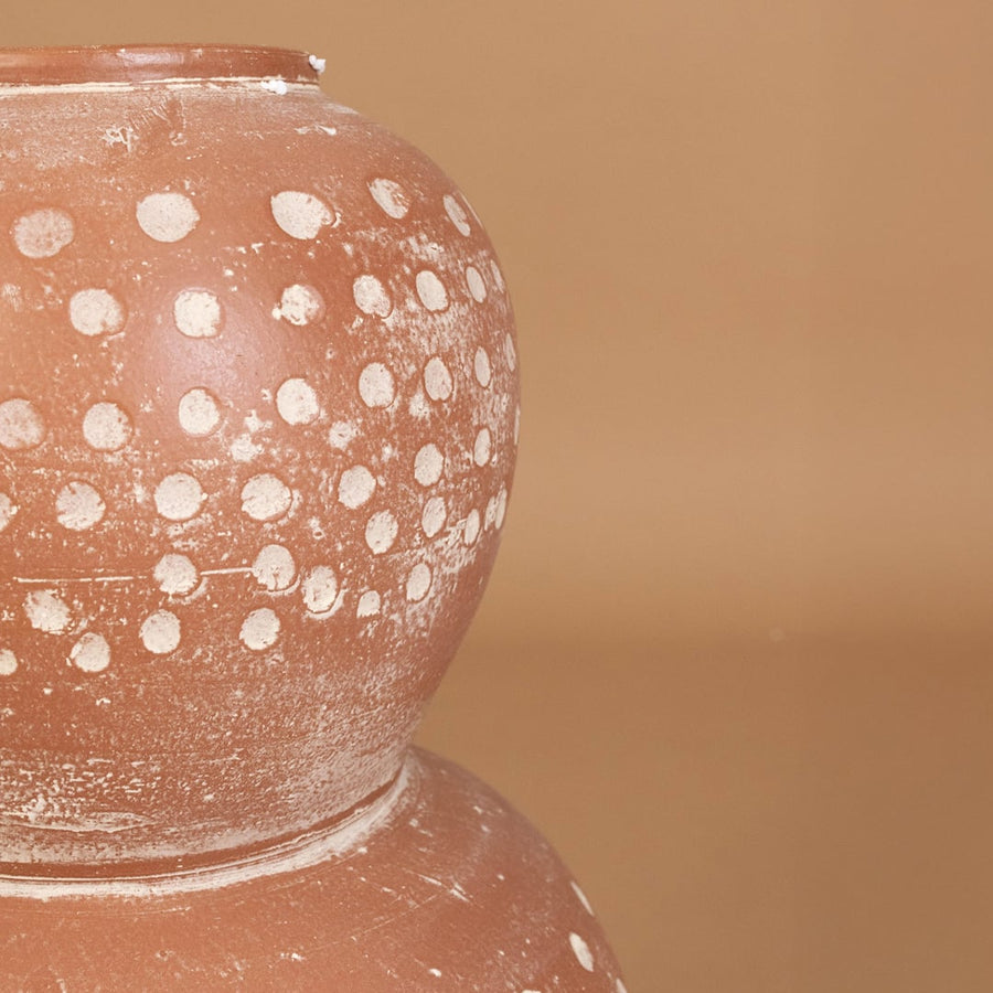 Closeup of brown terracotta decorative vase with white polka dots showing textured handcrafted detail for artistic modern home decor.