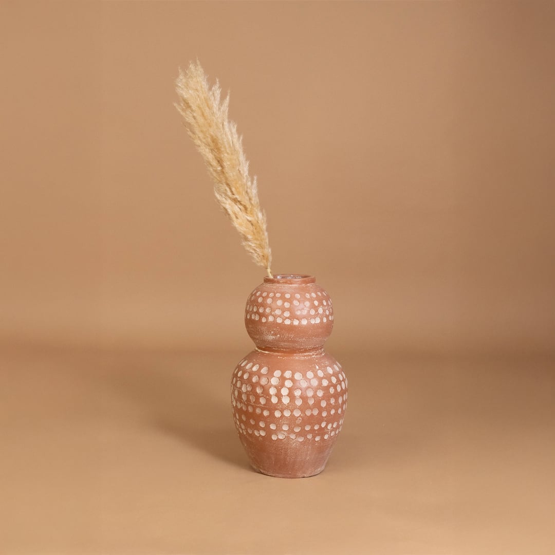 Brown terracotta decorative vase with white polka dots placed in a styled interior adding earthy artistic decor to shelves consoles and living spaces.