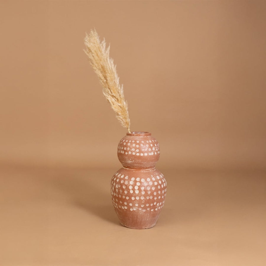 Brown terracotta decorative vase with white polka dots placed in a styled interior adding earthy artistic decor to shelves consoles and living spaces.