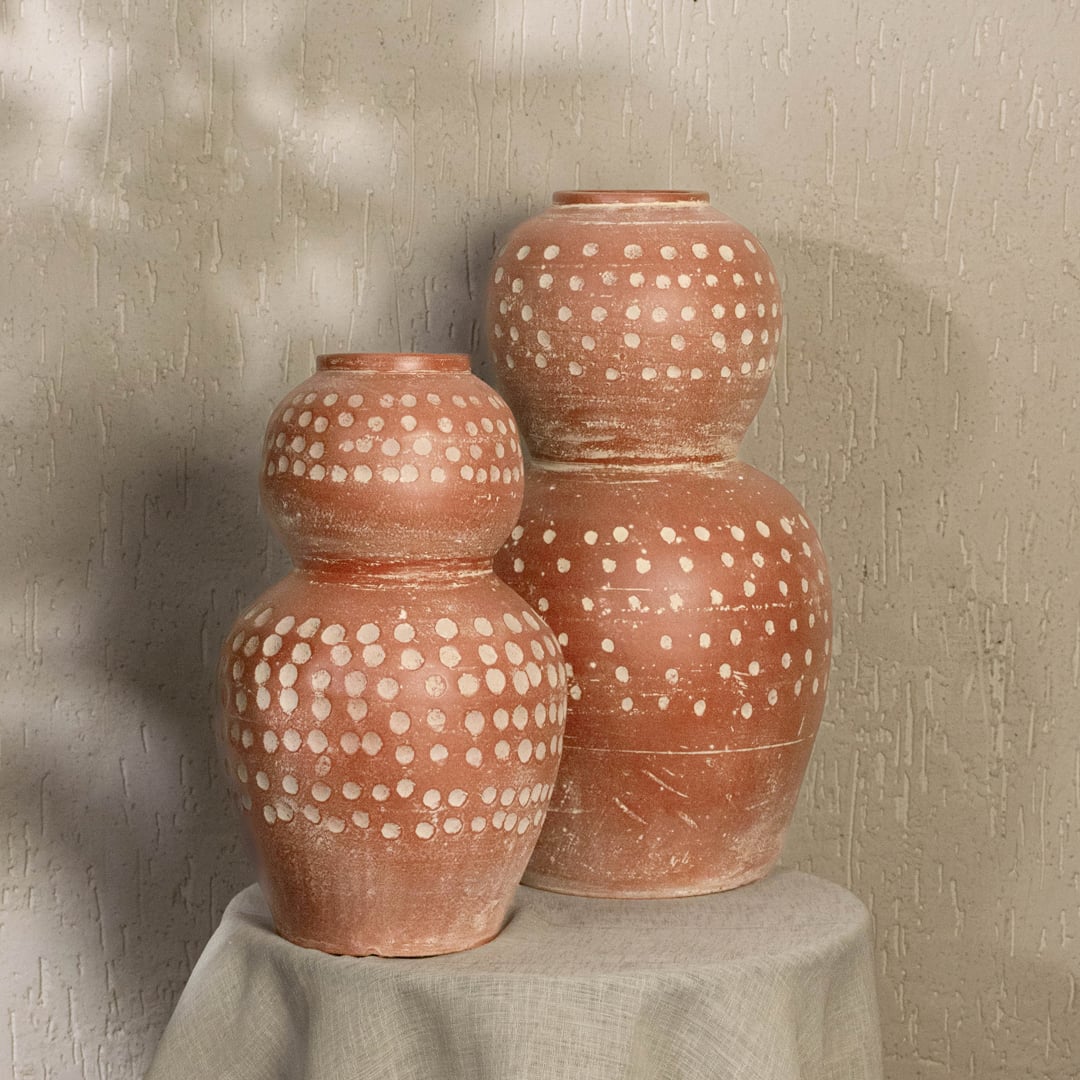 Brown terracotta decorative vase with white polka dots styled in a warm modern room adding earthy artistic decor to living rooms hallways and interiors.