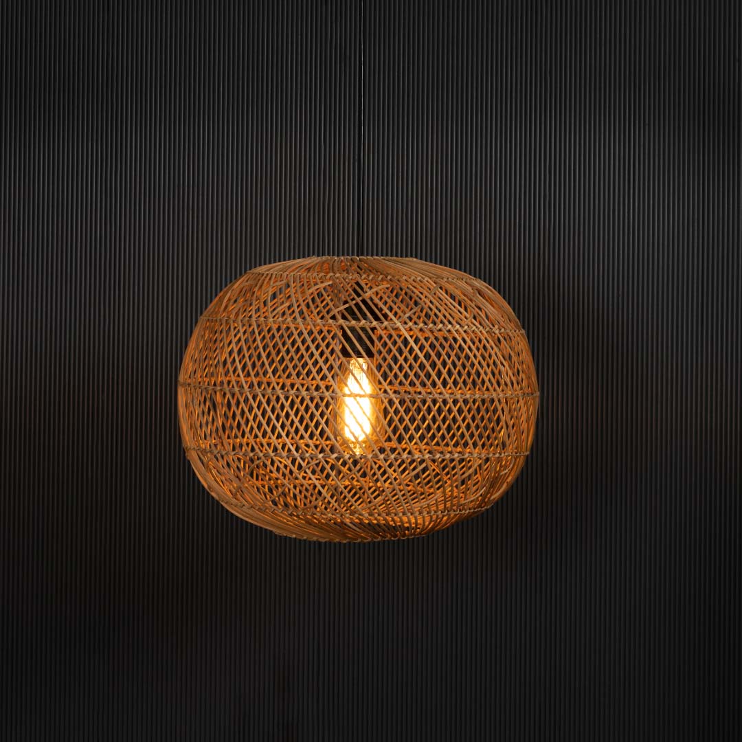 Round rattan pendant light glowing warmly on black background showcasing ambient light through woven shade.