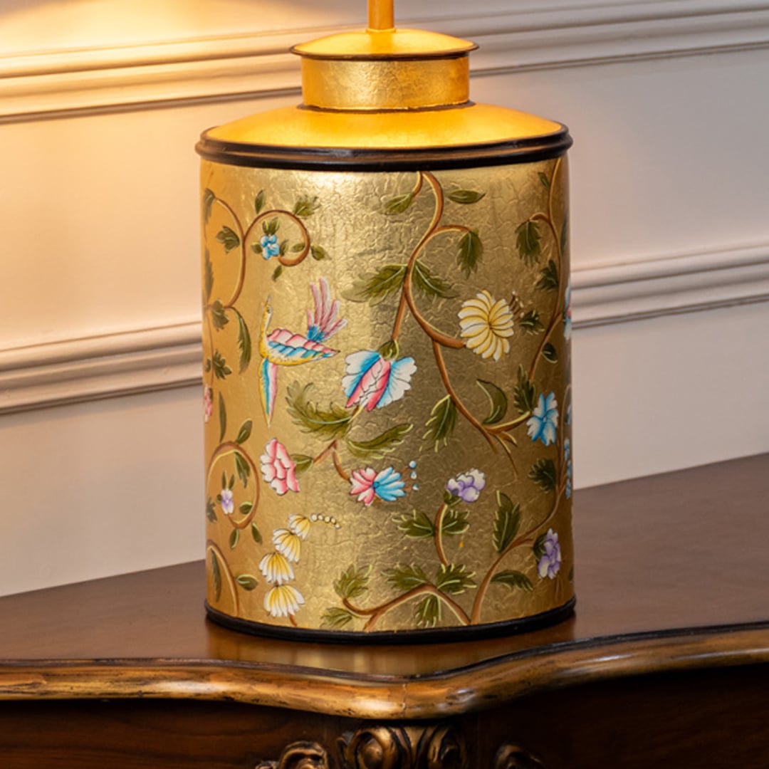 Table lamp closeup featuring colorful floral bird pattern on ceramic base with rich tones and polished gold accent.