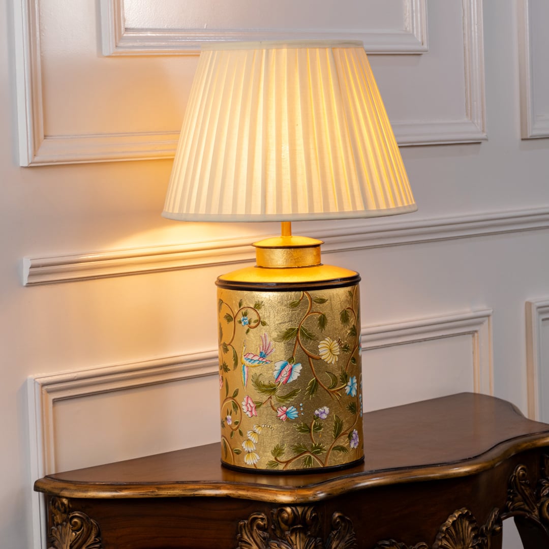 Table lamp with a decorative patterned ceramic base and warm pleated fabric lampshade placed on a white background.