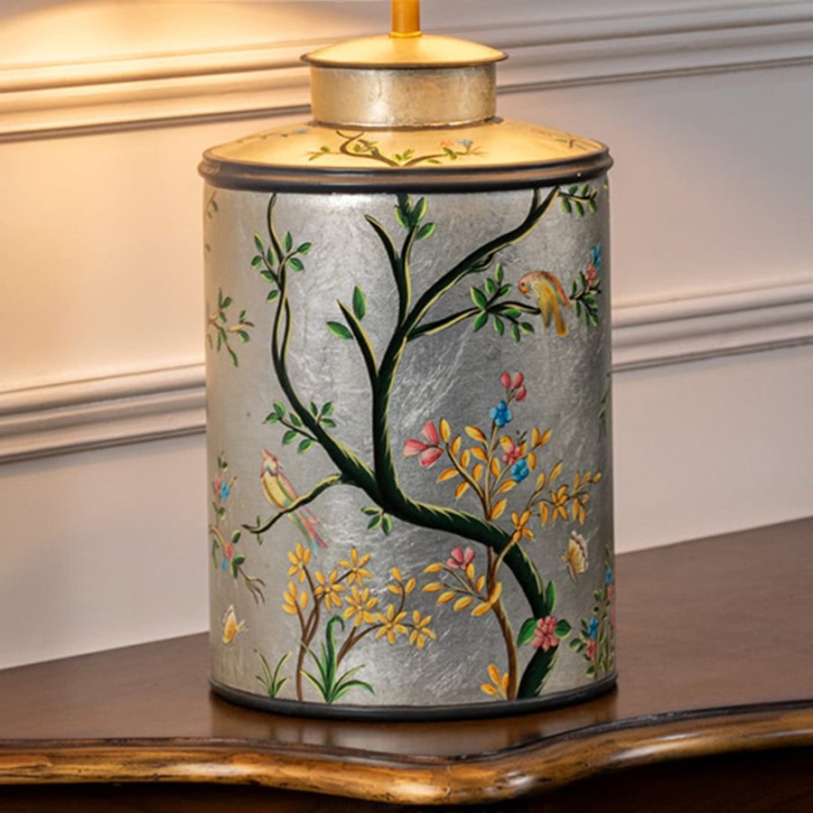 Table lamp closeup highlighting hand painted floral bird artwork on ceramic base with smooth glazed finish and gold detailing.