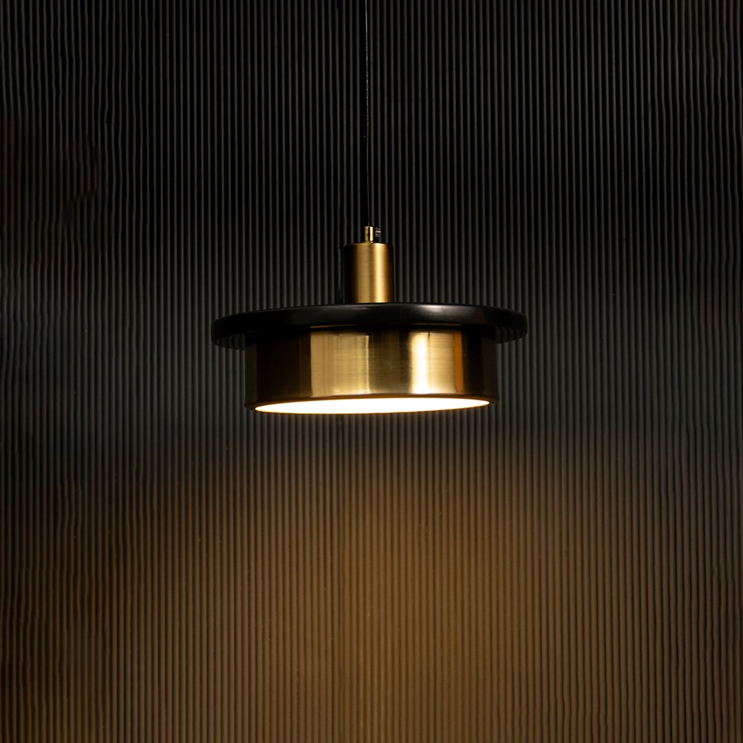 Black and gold metal pendant light illuminated warmly adding contemporary elegance to modern dining spaces.