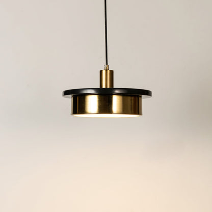 Gold metal pendant light illuminated to display elegant modern design with warm ambient lighting performance.