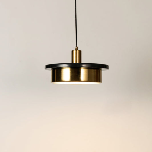 Gold metal pendant light illuminated to display elegant modern design with warm ambient lighting performance.