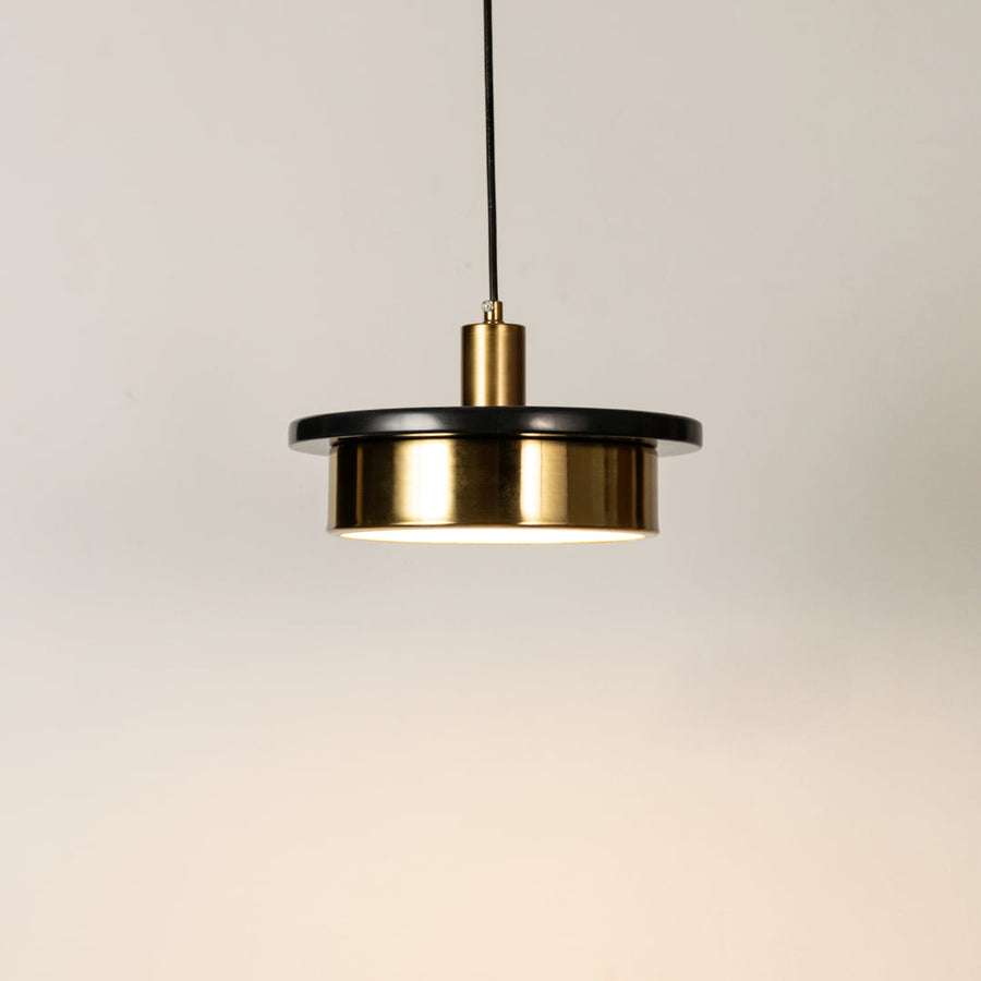 Gold metal pendant light illuminated to display elegant modern design with warm ambient lighting performance.
