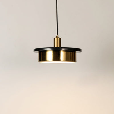 Gold metal pendant light illuminated to display elegant modern design with warm ambient lighting performance.