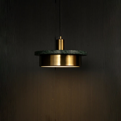 Green marble and metal disc pendant light hanging against dark textured wall with light on for stylish modern décor.