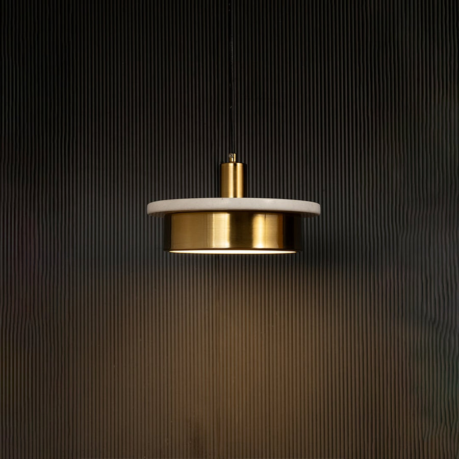 White marble and metal disc pendant light hanging against dark textured wall with light on for elegant soft décor.