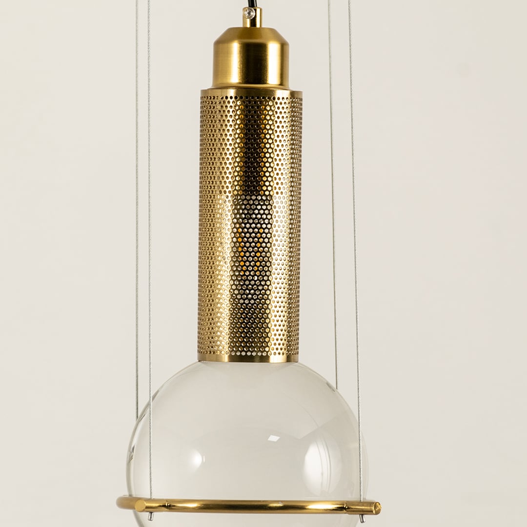Closeup of pendant light with frosted glass shade and gold metal cylinder highlighting premium materials and refined lighting craftsmanship.