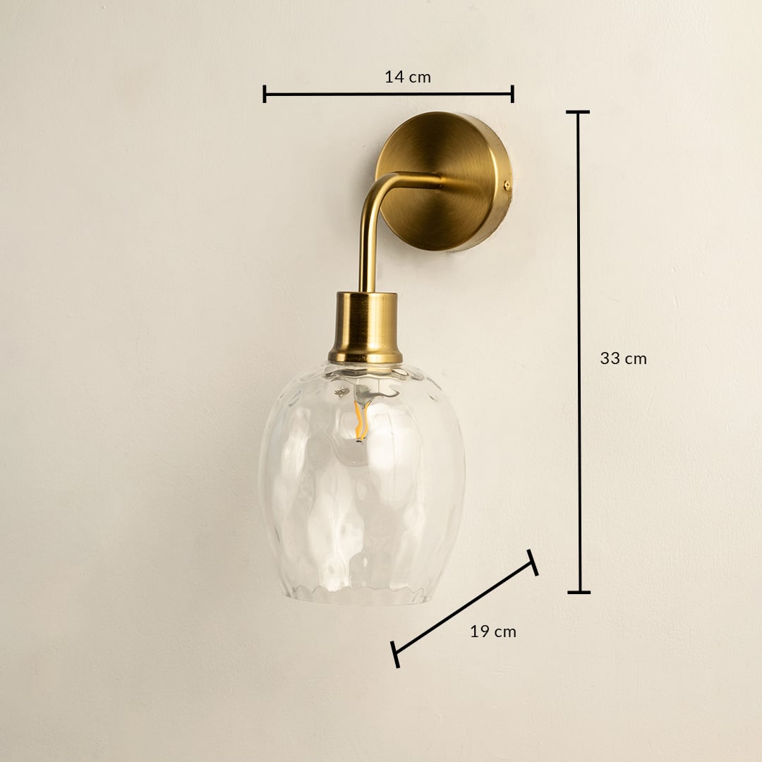 A glass and gold metal wall light measuring 33 cm height 19 cm depth and 14 cm width glowing warmly against a soft white wall creating elegant ambient lighting and refined décor.