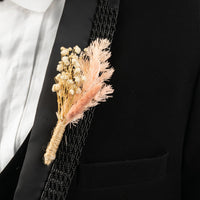Closeup of rustic boutonniere with dried flowers and pampas grass for groom wedding suit accessory.
