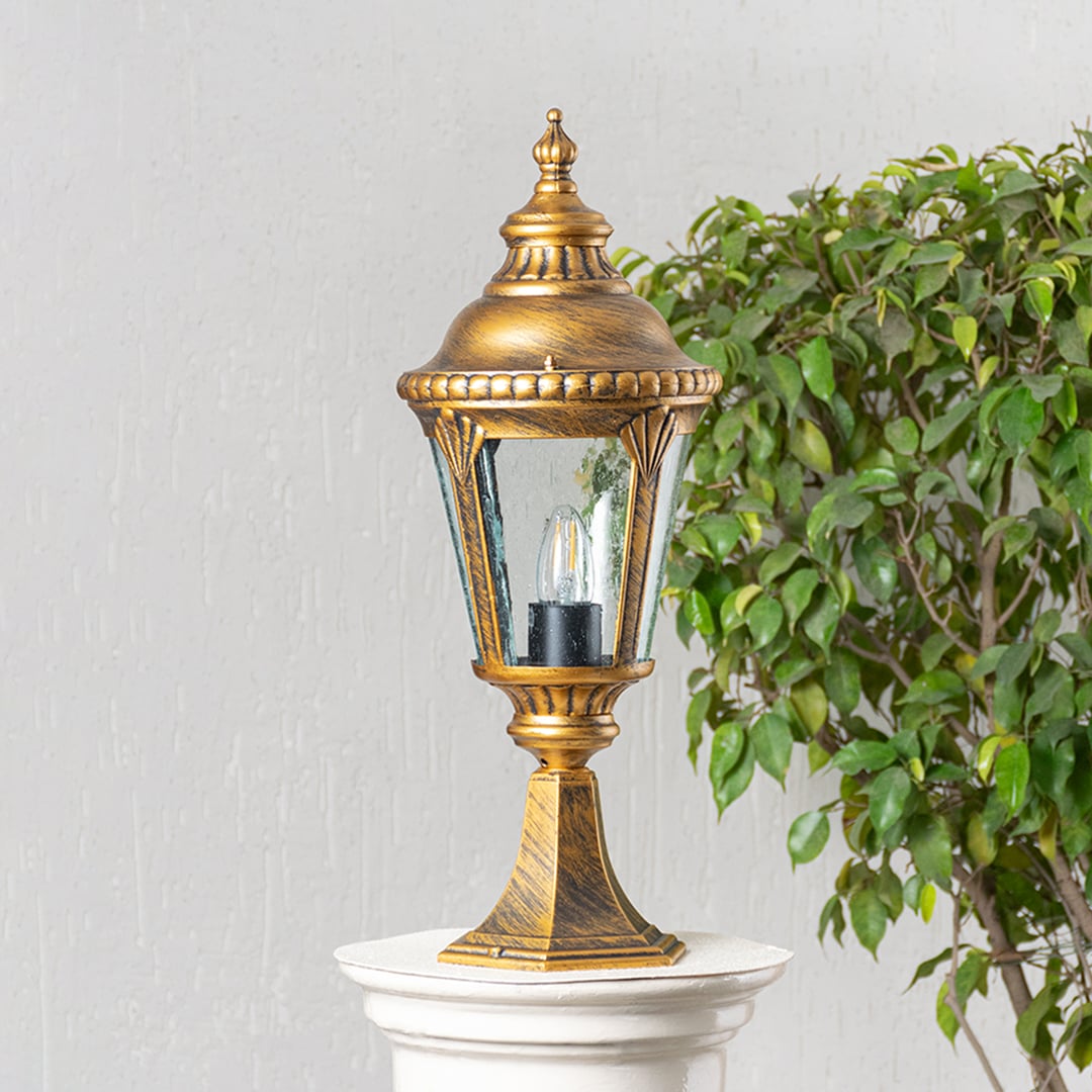Elegant golden pillar lamp placed on stone pillar with light off enhancing villa entrance and outdoor garden pathway decor.