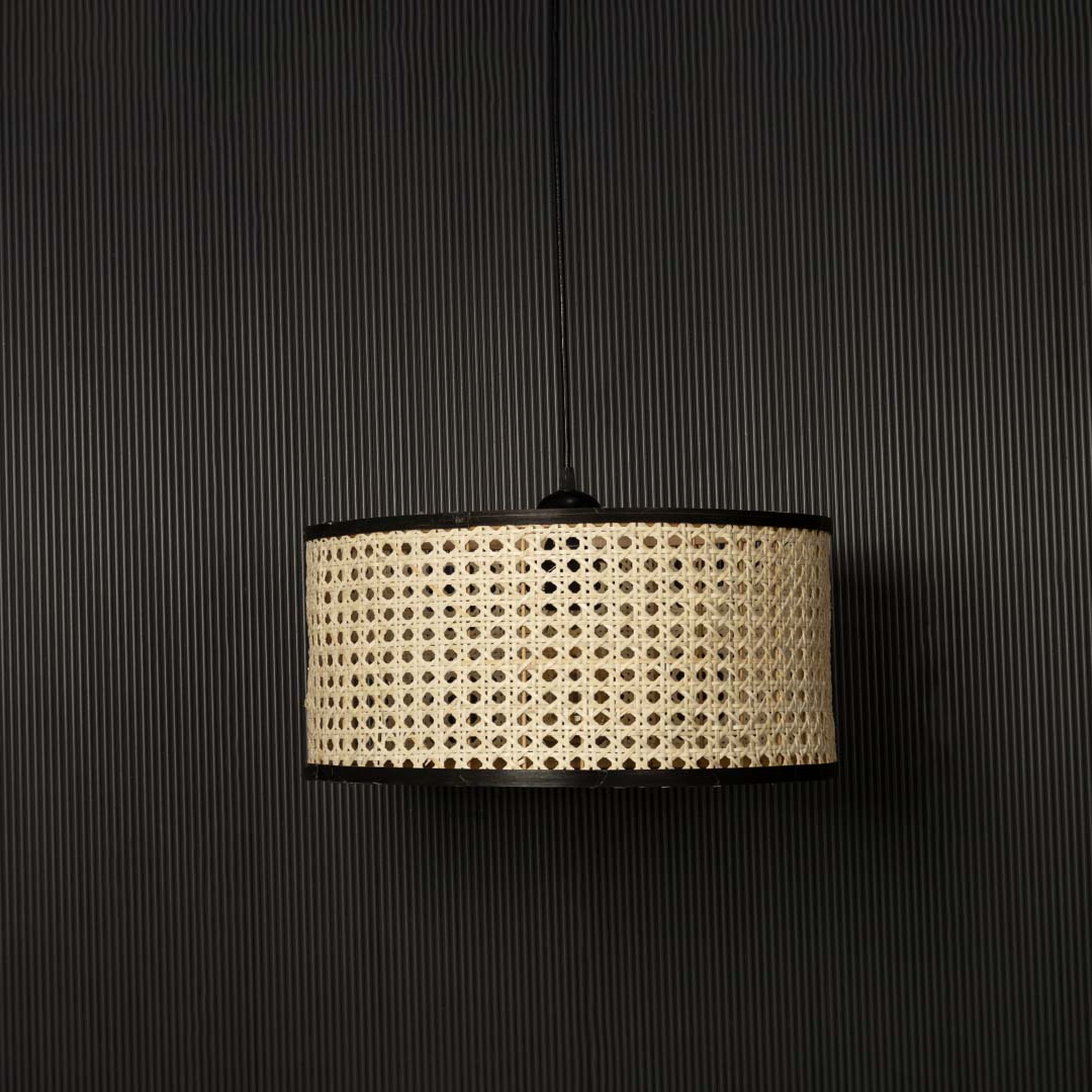 Natural cane pendant light displayed off against black background highlighting detailed handcrafted rattan weave.