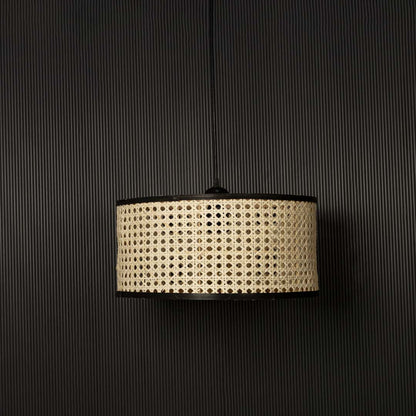 Natural cane pendant light displayed off against black background highlighting detailed handcrafted rattan weave.