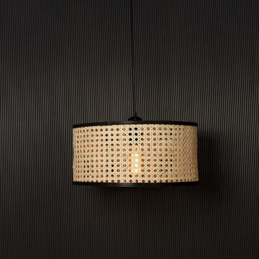 Rattan pendant light glowing through woven cane pattern casting warm ambient light on black background.