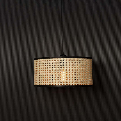 Rattan pendant light glowing through woven cane pattern casting warm ambient light on black background.
