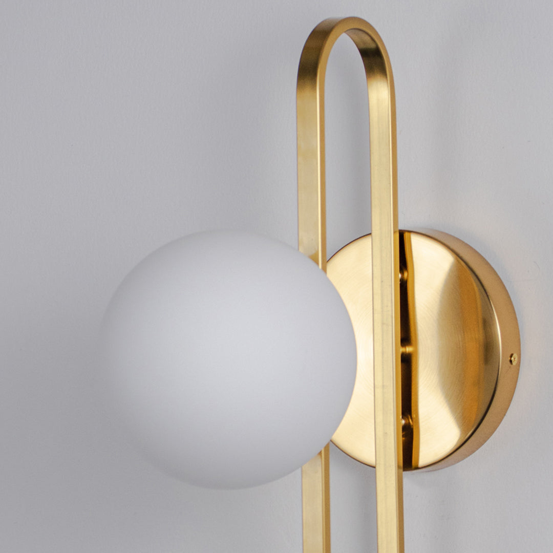 Minimal wall light with gold curved arm and white glass globe on neutral background modern elegant lighting for home decor.