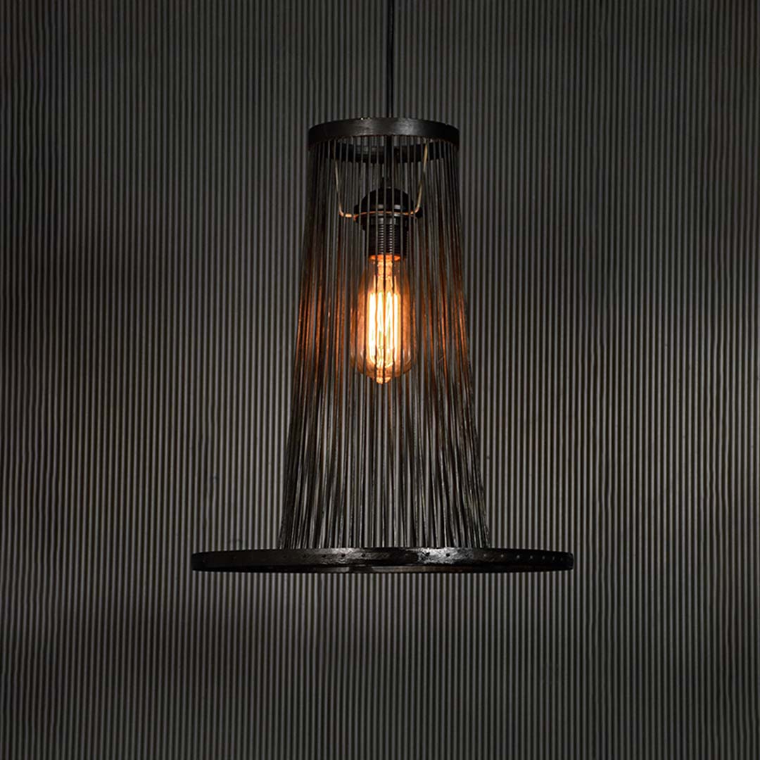 Black wire pendant light glowing warmly on dark background accentuating its sculptural frame and modern silhouette.