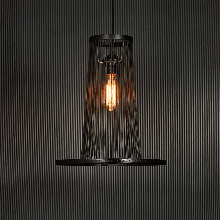 Black wire pendant light glowing warmly on dark background accentuating its sculptural frame and modern silhouette.
