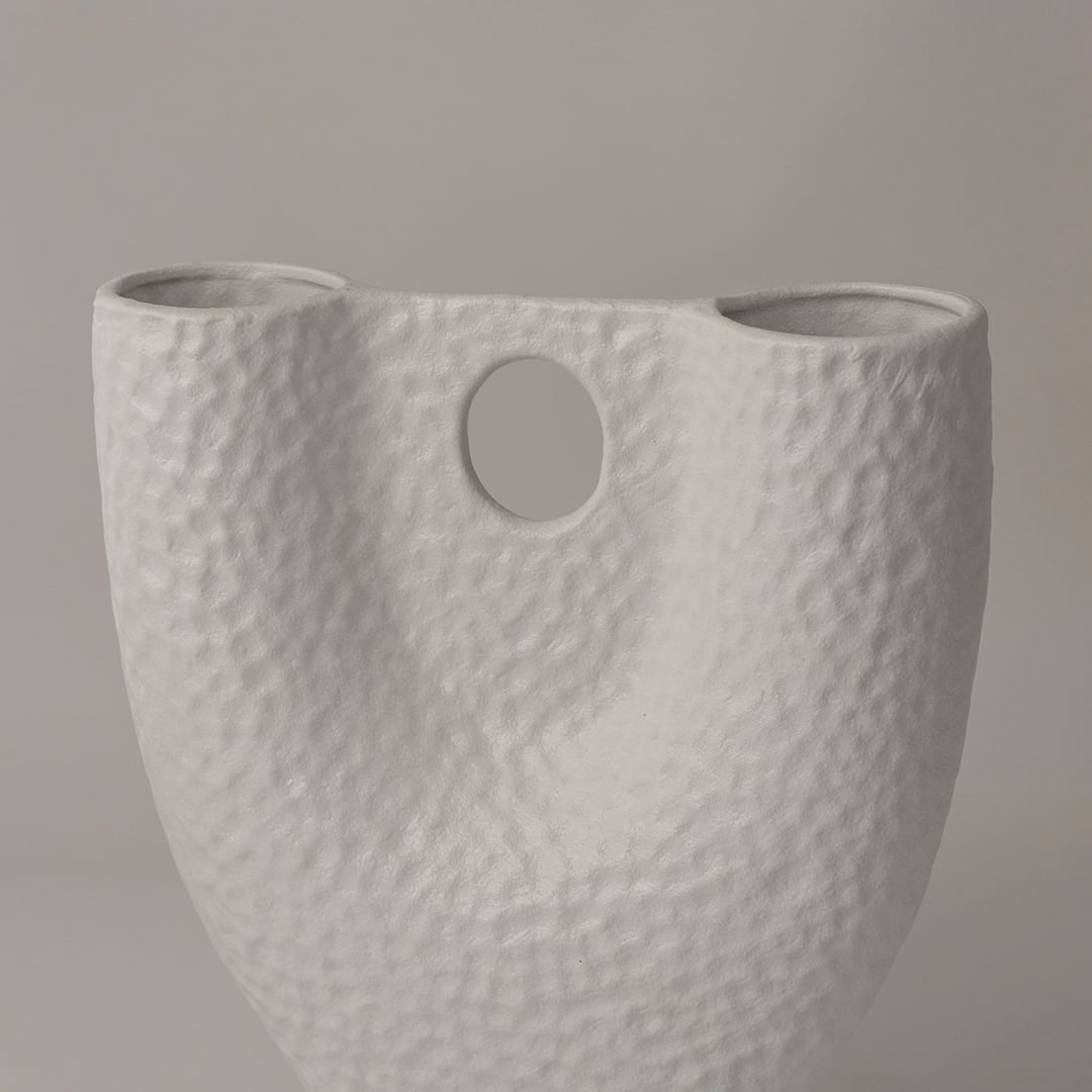 Closeup of matte white ceramic vase showing detailed hammered texture and circular cutout for modern handcrafted appeal.