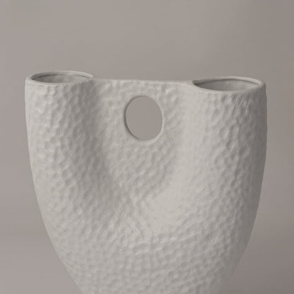 Closeup of matte white ceramic vase showing detailed hammered texture and circular cutout for modern handcrafted appeal.