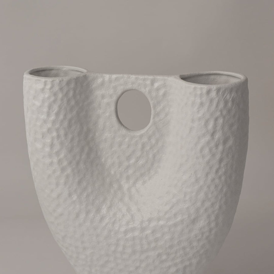 Closeup of matte white ceramic vase showing detailed hammered texture and circular cutout for modern handcrafted appeal.
