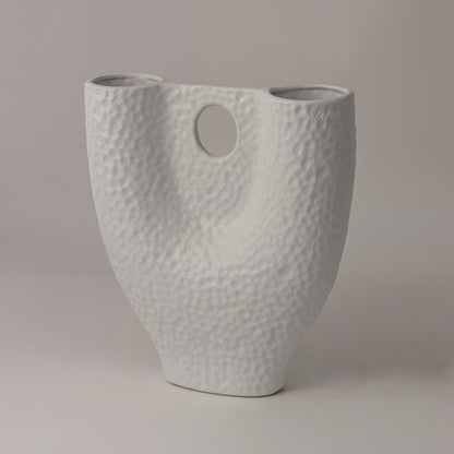 Side view of white textured ceramic vase with curved body and circular accent showing handcrafted matte finish artistry.