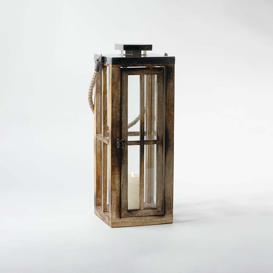Lit wooden lantern placed on a white background displaying its elegant handcrafted wood frame glass casing and stainless steel lid with rope handle for decorative use.