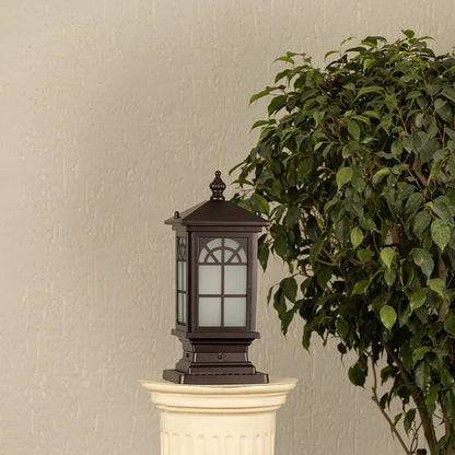 Black outdoor pillar light with ribbed glass Light On placed next to a lush green plant Lifestyle image for modern patio decor.