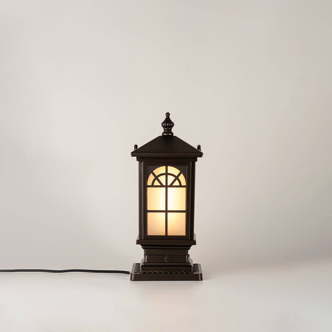 Vintage black outdoor gate light with warm glowing glass panels for elegant exterior decor use.
