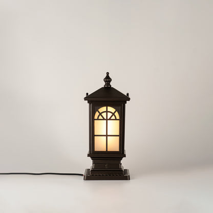 Vintage black outdoor gate light with warm glowing glass panels for elegant exterior decor use.