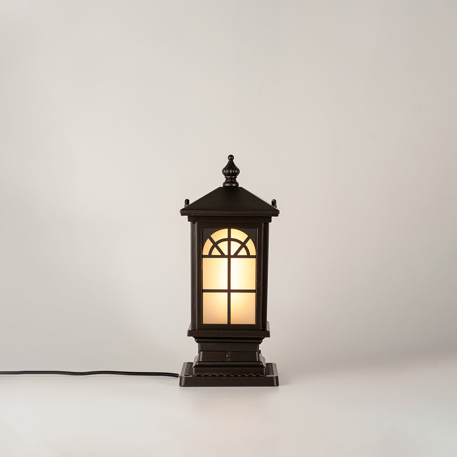 Vintage black outdoor gate light with warm glowing glass panels for elegant exterior decor use.